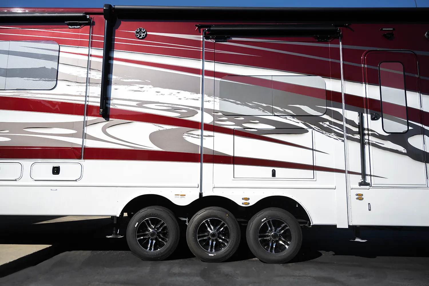 A side view of the triple axle, independent suspension on a Luxe 5th Wheel Toy Hauler.