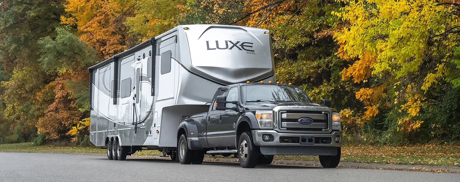 A Luxe Elite luxury fifth wheel, built by Luxe Fifth Wheel, in Autumn scenery.