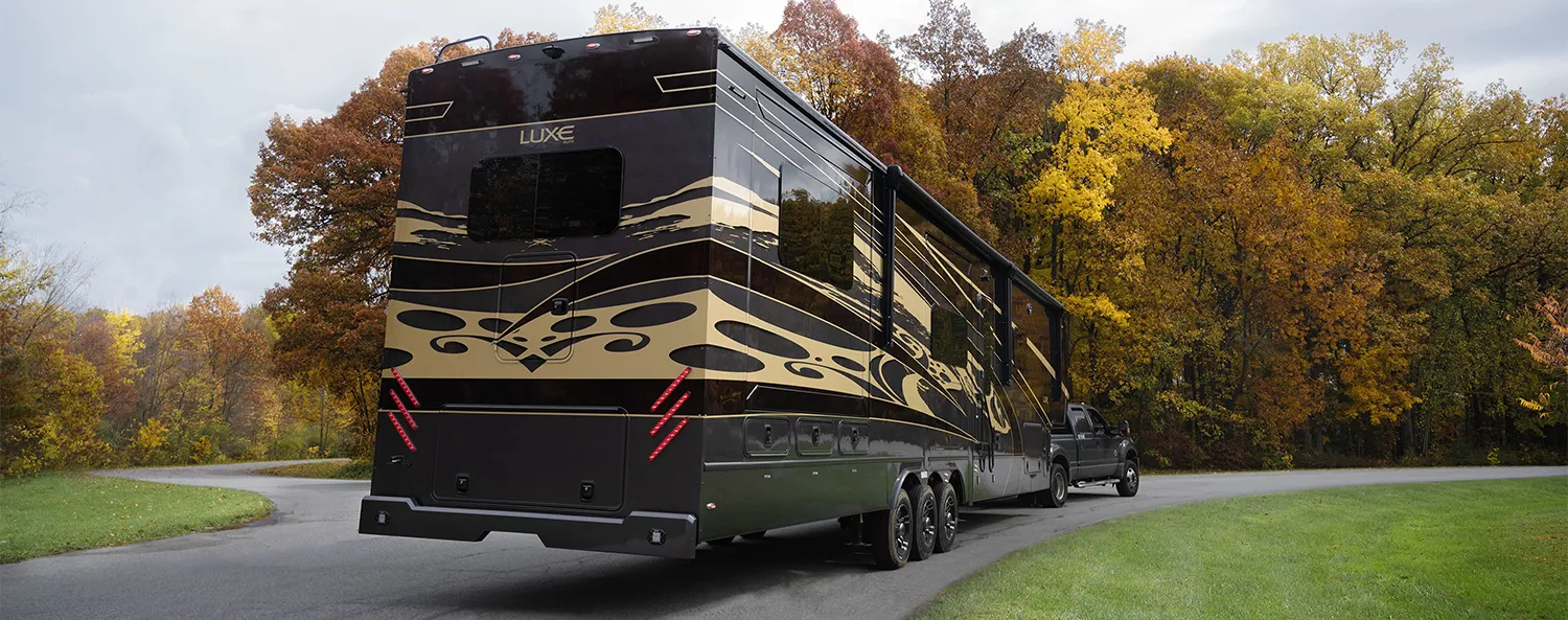 The Luxe Elite, one of the Best Luxury Fifth Wheels, driving in a state park in Autumn.