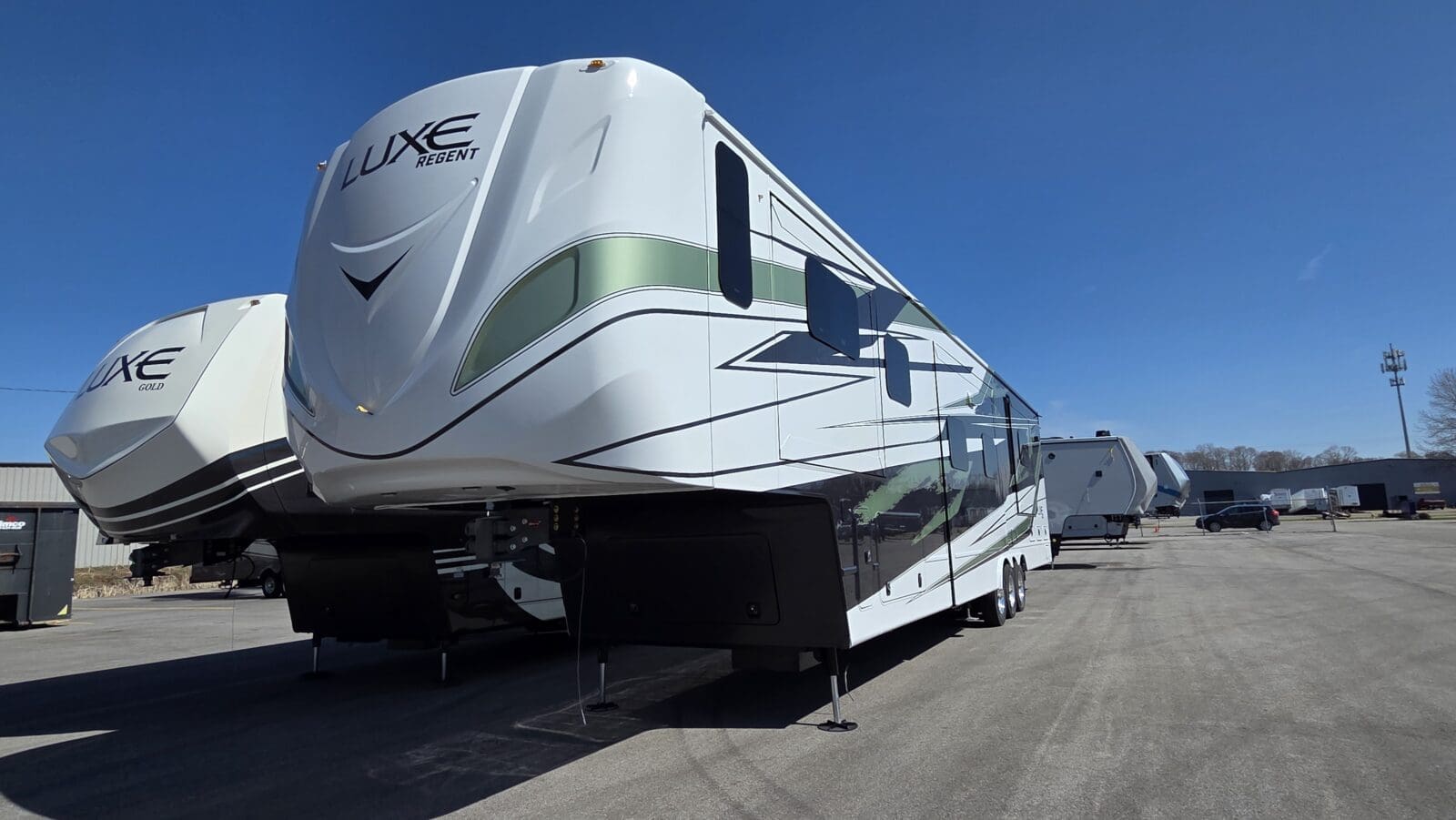 Luxe Regent and Gold luxury fifth wheel RVs with full-body paint and slide-outs under a clear sky